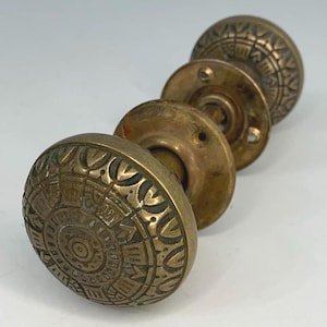 Könnte beinhalten: Ein Set aus drei Keramikbechern mit einer gesprenkelten, cremefarbenen Glasur. Jeder Becher hat ein anderes handgemaltes Design: ein blaues und grünes Blatt, eine gelbe Blume und eine rote Beere. Die Becher haben ein schlichtes, modernes Design.