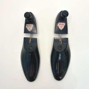 May include: A pair of black shoe trees with a knob at the top and a shoe-shaped form. Each tree has a label that reads "Dick's SHOES MEN" in a red and white shield design. The shoe trees are designed to maintain the shape of shoes.