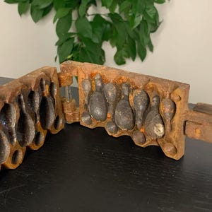 May include: A vintage metal mold for making bowling pins. The mold is made of two pieces that fit together. The mold is rusty and has a brown patina.
