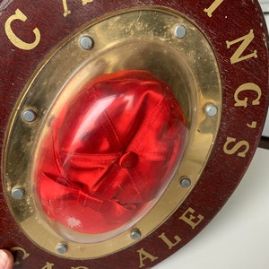 Peut inclure: Une enseigne en bois avec un cadre en m&eacute;tal dor&eacute; et une casquette de baseball en satin rouge &agrave; l'int&eacute;rieur. L'enseigne indique "Carling's Cap Ale".