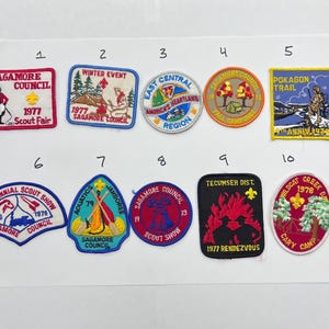 May include: A collection of ten vintage embroidered patches, featuring various designs and text. The patches include images of scouts, camp scenes, and text such as "Sagamore Council" and "Bicentennial Scout Show".