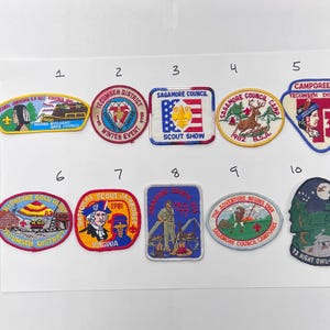 Op de afbeelding: Een verzameling van tien vintage Boy Scout-patches. De patches tonen verschillende ontwerpen, waaronder een Indiaans profiel, een hert, de Amerikaanse vlag en tekst zoals "Tecumseh District" en "Sagamore Council Camporee".