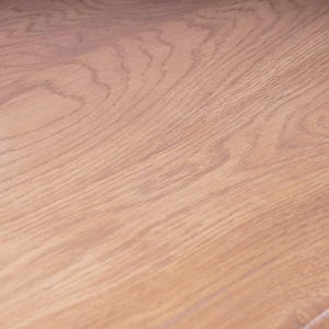 May include: A light brown wooden surface featuring a prominent natural grain pattern with swirling lines and organic textures. The wood displays a warm, tan color palette with visible knots and elongated fibers running across the flat plane.