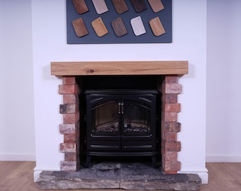 May include: A black wood-burning stove with a glass door is set into a brick fireplace with a wooden mantel. The fireplace is in a room with white walls and a wood floor.