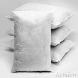 May include: Four white pillow inserts stacked on top of each other. The pillow inserts are made of a soft, fluffy material.