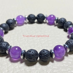 Może przedstawiać: Bransoletka z naprzemiennymi czarnymi koralikami z lawy wulkanicznej i fioletowymi kamieniami szlachetnymi. Bransoletka zawiera srebrne metalowe akcenty i napis "truevalue Gemstone". Idealna do codziennego noszenia, ok. 19 cm obwodu.