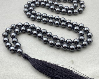 May include: A black beaded necklace with a black tassel. The beads are round and have a shiny finish.