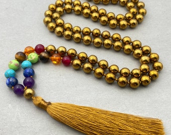 May include: A gold hematite mala necklace with a rainbow of chakra stones and a gold tassel.