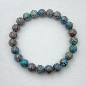 Puede incluir: Un brazalete hecho de cuentas azules y marrones moteadas.