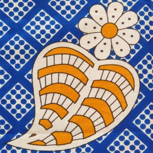 May include: A white paisley design with orange and black accents on a blue background with white polka dots. The paisley design features a flower with a yellow center.