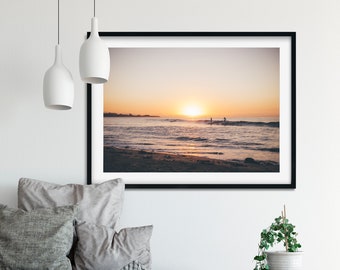 Peut inclure: Une photographie encadrée d'une scène de plage avec deux personnes debout dans l'eau au coucher du soleil. Le soleil se couche sur l'océan, projetant une lueur chaude sur l'eau et le sable.