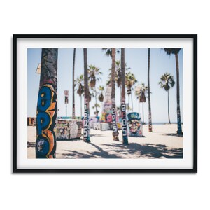 Peut inclure: Gros plan sur des troncs de palmiers peints de graffitis color&eacute;s sur une plage. Les troncs sont nets, tandis que l'arri&egrave;re-plan est flou.