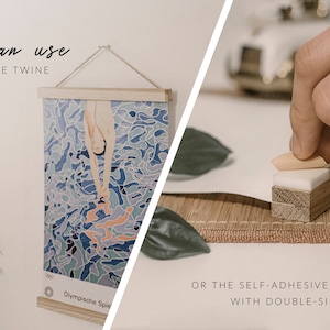 May include: A wooden poster hanger with a jute twine hanging system. The hanger is holding a poster with a blue and orange abstract design. The text "Olympische Spiele" is visible on the poster. The image shows how to hang a poster using self-adhesive foam or double-sided tape.