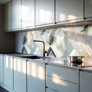May include: A modern kitchen with grey cabinets and a backsplash featuring a geometric pattern of white, blue and gold marble tiles.