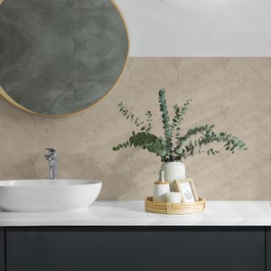 May include: A white ceramic bathroom sink with a chrome faucet, a white ceramic vase with green eucalyptus branches, and a wooden tray with a white ceramic soap dispenser, a white ceramic soap dish, and a white picture frame.