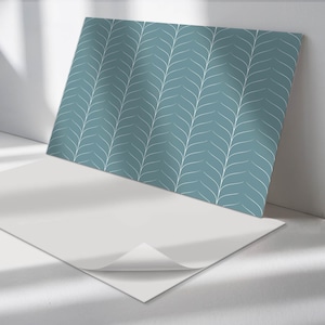 May include: A sheet of teal blue wallpaper with a white leaf pattern. The wallpaper is partially peeled back to reveal the adhesive backing.