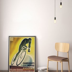 May include: Vintage poster advertising the 1939 World Cycling Championships in Milan-Varese, Italy. The poster features a cyclist in a yellow and green jersey riding a bicycle on a yellow background. The text on the poster reads "Campionati del Mondo di Ciclismo" and "Milano-Varese 27 Agosto-3 Settembre 1939 - XVII."