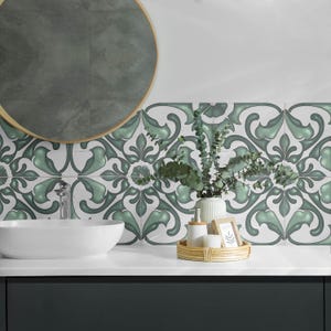 Può includere: Un mobile da bagno con un piano in bianco e uno schienale in piastrelle con motivo verde scuro e bianco. Uno specchio rotondo è appeso sopra il lavabo. Una piccola pianta in un vaso bianco si trova sul piano, insieme a una bottiglia di sapone e un piccolo vassoio di legno.
