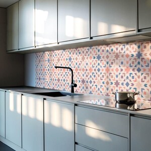Peut inclure: Une cuisine moderne avec des armoires grises et un robinet noir. La crédence est un carrelage à motifs géométriques roses, bleus et blancs.
