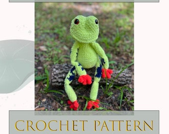 May include: Crochet pattern for a green tree frog named Fred. The frog is sitting on a log with red and blue accents.