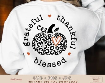 May include: A white sweatshirt with a black and white leopard print pumpkin design. The pumpkin has a small orange heart in the center. The text "grateful & thankful blessed" surrounds the pumpkin.