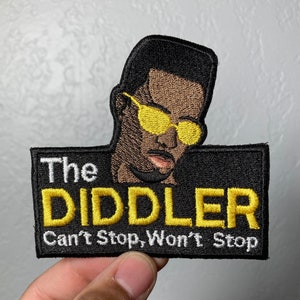 May include: Black and yellow embroidered patch with a cartoon image of a man wearing sunglasses. The text on the patch reads "The Diddler Can't Stop, Won't Stop."