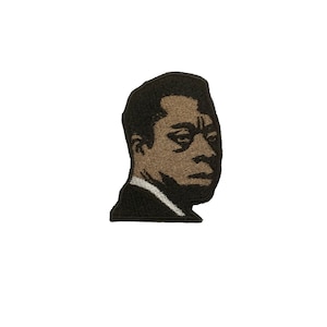 May include: Black and white embroidered patch of a man wearing a suit and glasses. The man is looking to the side.