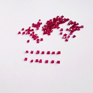 Può includere: Un grande mucchio di piccole pietre preziose quadrate rosse, con una fila più piccola delle stesse pietre preziose disposte in due linee parallele.