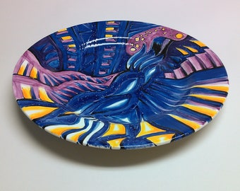 Hand painted round ceramic plate in blues, purples and oranges