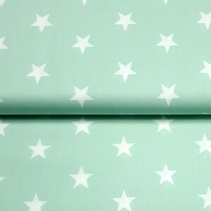 Könnte beinhalten: Ein mintgrüner Stoff mit einem weißen Sternenmuster. Der Stoff ist in der Mitte gefaltet, sodass das Muster auf beiden Seiten sichtbar ist.