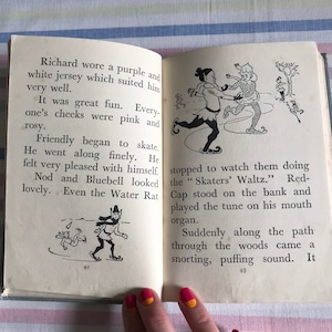 May include: An open book with illustrations of children ice skating. The text on the page reads "Richard wore a purple and white jersey which suited him very well. It was great fun. Every-one's cheeks were pink and rosy. Friendly began to skate. He went along finely. He felt very pleased with himself. Nod and Bluebell looked lovely. Even the Water Rat stopped to watch them doing the "Skaters' Waltz." Red-Cap stood on the bank and played the tune on his mouth organ. Suddenly along the path through the woods came a snorting, puffing sound. It"