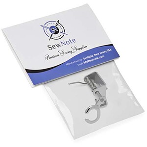 May include: A silver sewing machine foot attachment with a spring and a hook. The foot is designed to help with sewing projects.