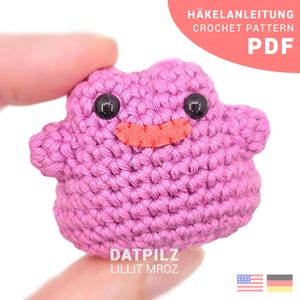 Könnte beinhalten: Ein handgefertigtes Häkeltier in hellem Lila, mit schwarzen Knopfaugen und einem roten Filzmund. Das Spielzeug hat die Form eines Kleckses. Der Text auf dem Bild lautet "HÄKELANLEITUNG CROCHET PATTERN PDF" und "DATPILZ LILLIT MROZ".