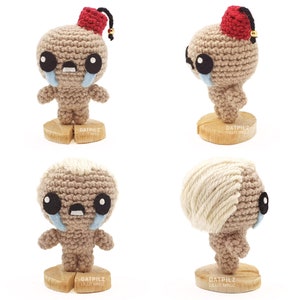 May include: Four crocheted figures with sad faces and red and white hats. The figures are standing on wooden bases with the text 'DATPILZ LILIT MROZ' on them.