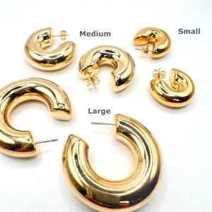 May include: Three pairs of gold hoop earrings in different sizes: small, medium, and large. The earrings are all made of a thick, shiny metal.