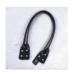 Puede incluir: Un par de asas de bolso de cuero negro con remaches de metal plateado.