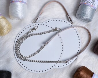 May include: Two white round leather pieces with holes for stitching, a silver chain, and a brown leather strap. The leather pieces are for making a bag or purse.