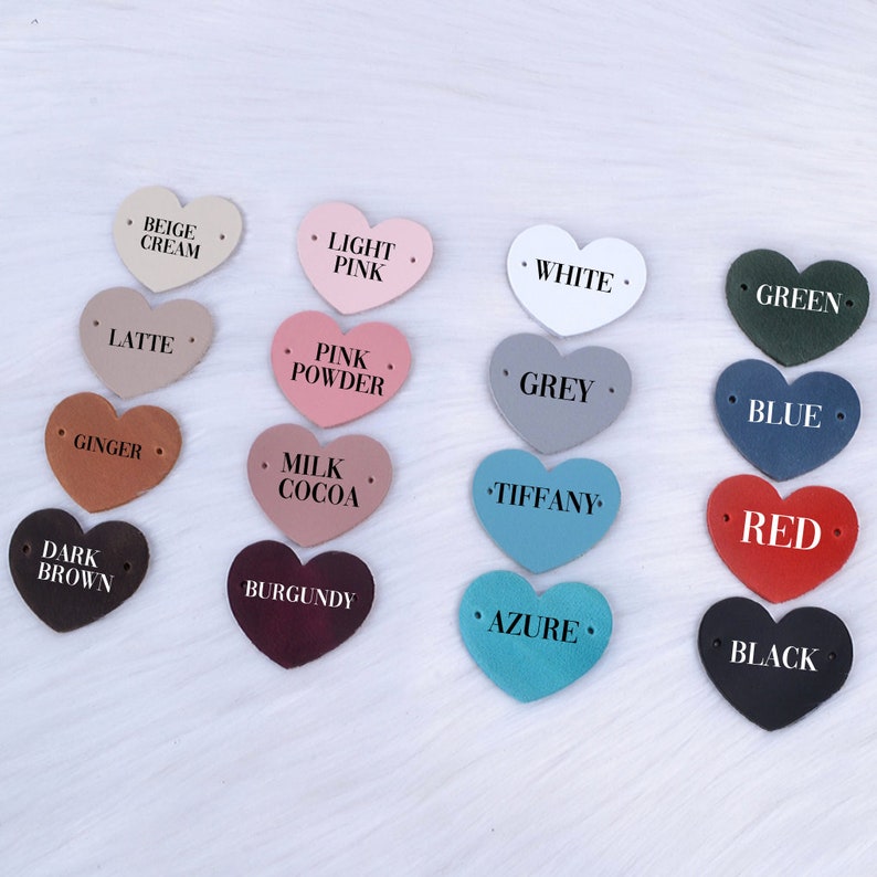 May include: Assortment of 16 heart-shaped leather labels in various colors, including beige, pink, white, green, blue, red, brown, burgundy, and turquoise. Each label features a different color name printed in black.