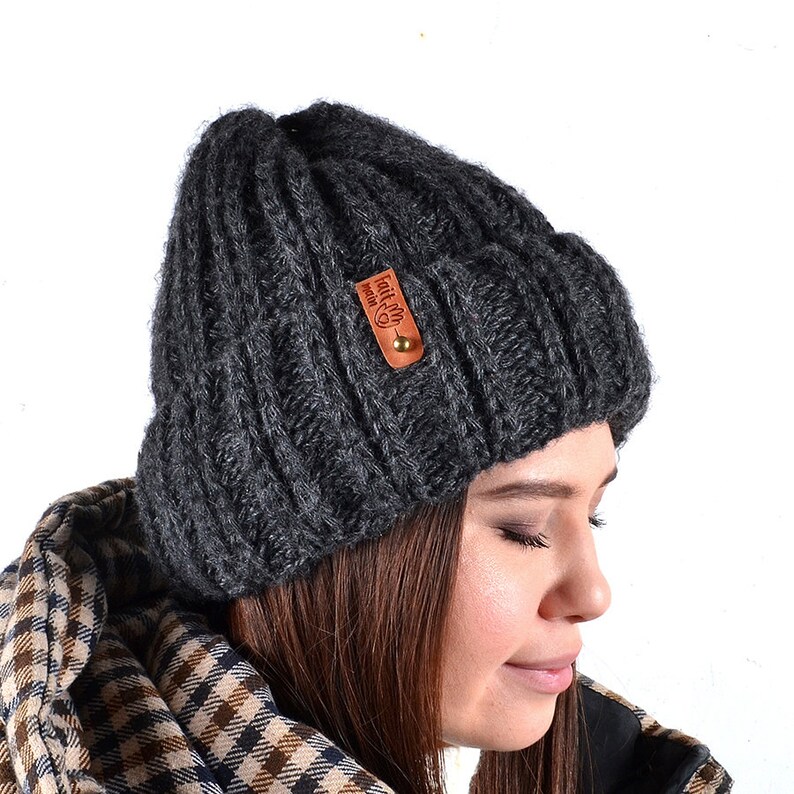 May include: A dark gray knitted beanie with a brown leather patch that says "Fall in love with nature".