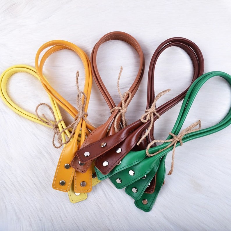Puede incluir: Cinco correas de cuero en diferentes colores: amarillo, naranja, marr&oacute;n, verde y marr&oacute;n oscuro. Las correas est&aacute;n atadas con cuerda y tienen remaches met&aacute;licos.