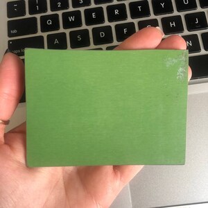 May include: A solid green square-shaped piece of material. The material has a slightly textured surface.