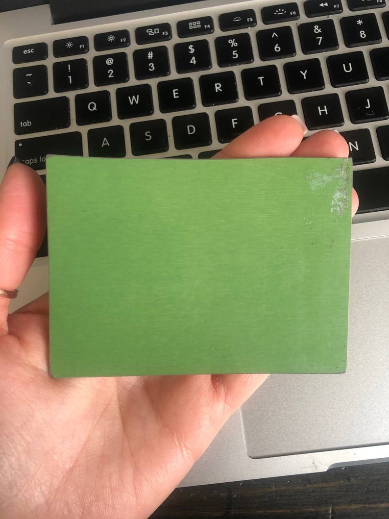 May include: A solid green square-shaped piece of material. The material has a slightly textured surface.