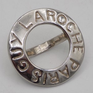 May include: A silver ring with the words "LA ROCHE PARIS" engraved around the band.