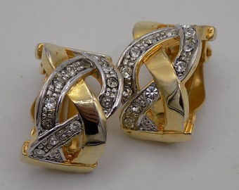 Op de afbeelding: Een paar gouden en zilveren oorbellen met een geweven ontwerp en heldere strass steentjes.
