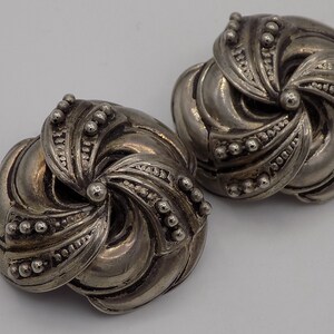 Peut inclure: Une paire de boucles d'oreilles argent&eacute;es avec un motif en spirale. Les boucles d'oreilles sont en m&eacute;tal et ont une surface textur&eacute;e.