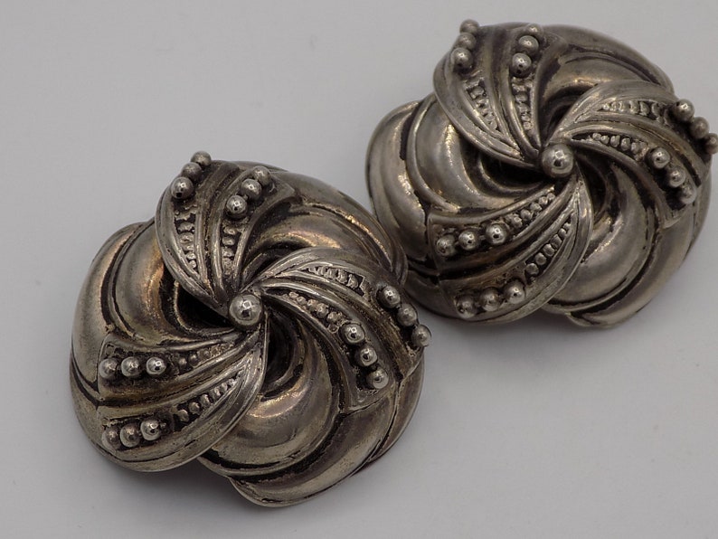 Peut inclure: Une paire de boucles d'oreilles argent&eacute;es avec un motif en spirale. Les boucles d'oreilles sont en m&eacute;tal et ont une surface textur&eacute;e.
