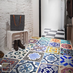 May include: A hallway with a white brick wall, a wooden crate with a gray tote bag on top, and a floor covered in colorful patterned tiles. The tiles are arranged in a mosaic pattern and feature blue, green, yellow, and red colors.