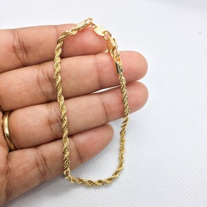 Könnte beinhalten: Ein goldenes Armband mit einer Seilketten-Optik und einem Karabinerverschluss.