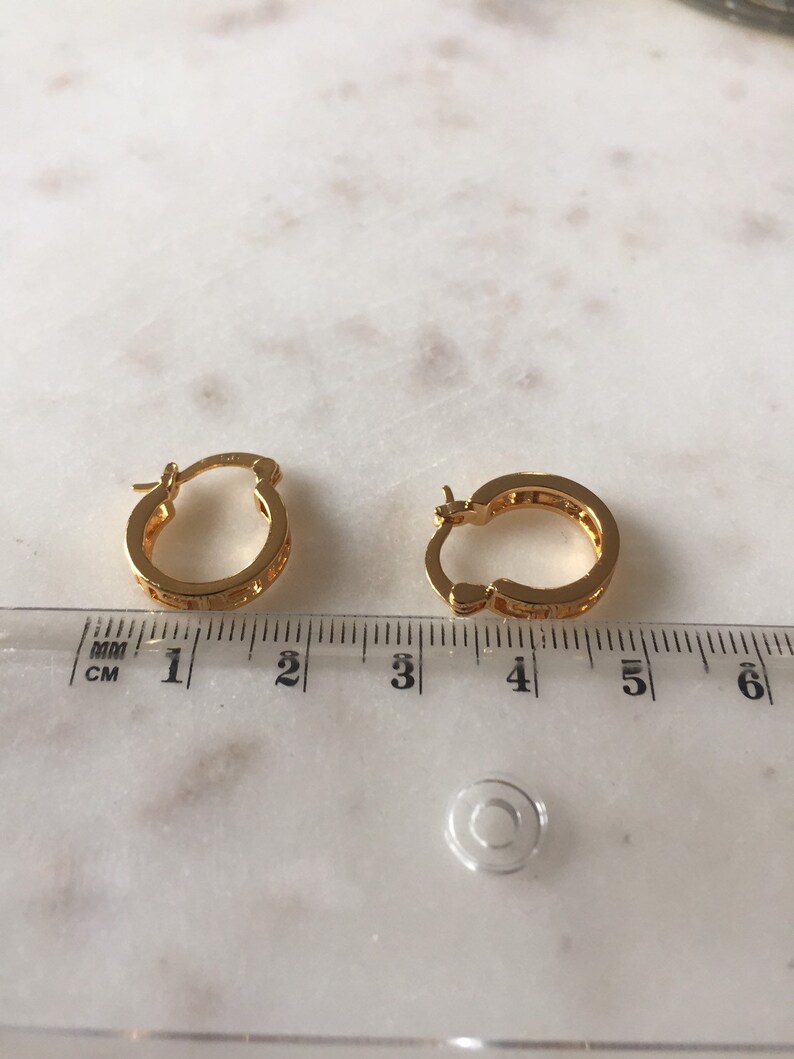 May include: A pair of gold hoop earrings with a textured design. The earrings are approximately 1.5 inches in diameter.