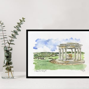 May include: Watercolor painting of a classical gazebo with columns, set in a green landscape under a blue sky. The artwork is framed in a black frame and includes the artist's signature.